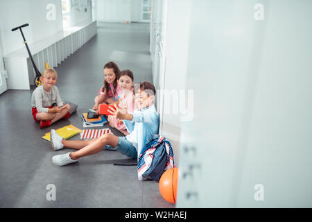 Dark-haired écolier faisant de beaux selfies camarades Banque D'Images