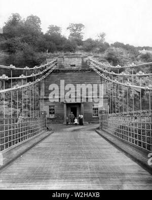 L'Union Pont des Chaînes et Toll House sur le côté anglais de la passerelle. La photographie a été prise en 1899 et 1900 environ et la avec la famille Roxburgh en dehors de leur maison. La Toll House a été démolie dans les années 1950. Le pont porte encore la circulation et est le plus vieux pont suspendu du monde. Traverser la rivière Tweed reliant l'Angleterre et l'Ecosse. Le pont est près du village de Skegness et a été conçu par le capitaine Samuel Brown de RN. Banque D'Images