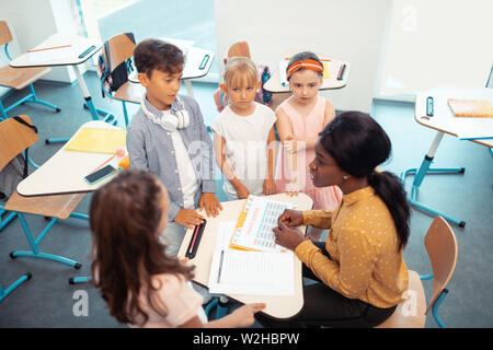 Vue de dessus d'enfants debout autour de leur professeur après leçon Banque D'Images