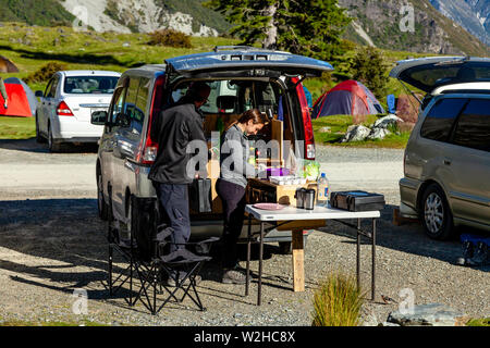 Deux personnes préparer un repas à l'extérieur d'un camper Van, le White Horse Hill camping (près de Mt Cook Village), Mt Cook National Park, South Island, New Zealand Banque D'Images