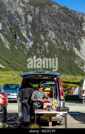 Deux personnes préparer un repas à l'extérieur d'un camper Van, le White Horse Hill camping (près de Mt Cook Village), Mt Cook National Park, South Island, New Zealand Banque D'Images