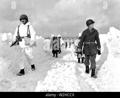 Les fantassins américains d'une division blindée de mars une route au sud-est de naissance, Belgique. Remarque La hauteur de l'amoncellement de neige de chaque côté de la route. 1/22/45. Co. C, 23e Armd. Inf, bn., 7e Armd. Banque D'Images