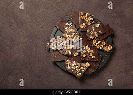 Morceaux de chocolat noir aux noisettes sur la plaque noire Banque D'Images