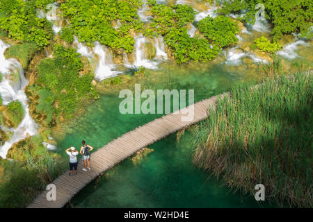 Les randonneurs sur le chemin de ronde passant cascades d'eau vers le bas dans le lac Kaluđerovac couleur turquoise au parc national des Lacs de Plitvice, Croatie Banque D'Images