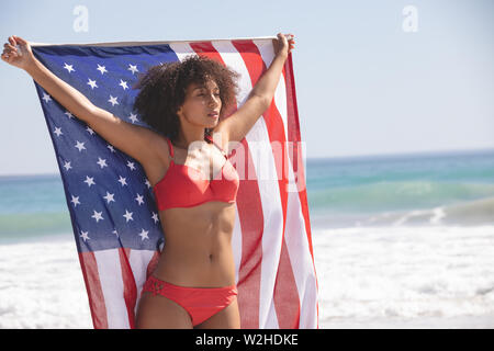 Woman in bikini holding drapeau américain sur la plage Banque D'Images