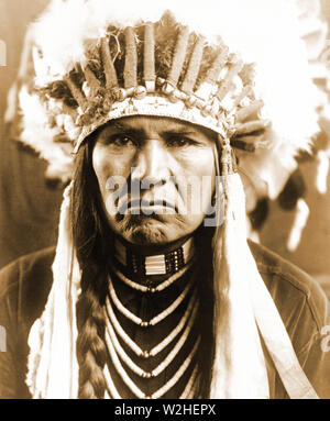 Edward S. Curtis indiens des États-Unis - Nez Percé l'homme en pleine plume coiffure, cheveux tressés, colliers et ca. 1910 Banque D'Images