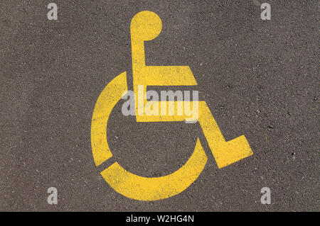 Close up photo de handicap parking sign désactiver jaune dessiné sur le bitume d'une rue de Lugano, Tessin - Suisse Banque D'Images