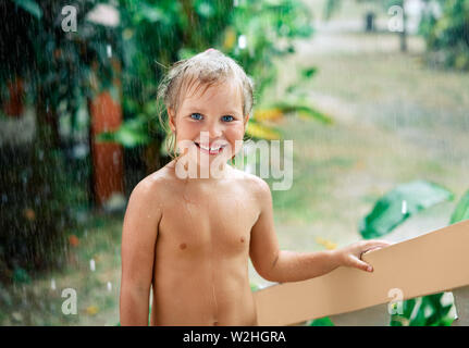 Close up portrait of cute little girl vivez l'été à la pluie. Gouttes tomber sur son visage, sourire de l'enfant. l'enfance, les émotions et les vacances Banque D'Images