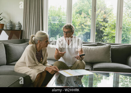 Couple actif domestique calcul des factures au sofa in living room Banque D'Images