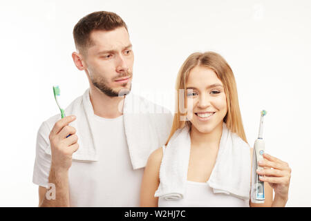 Joli couple dans des tenues aux couleurs coordonnées avec les serviettes blanches sur les épaules sur le fond blanc les deux brosses à dents. Banque D'Images