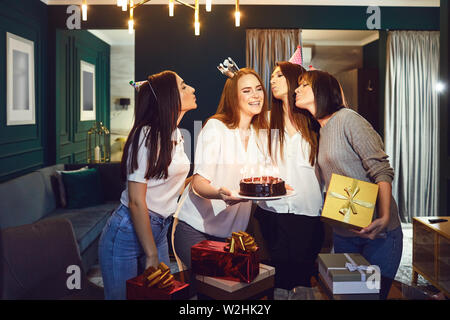 Les jeunes femmes élégantes avec un gâteau et des cadeaux pour féliciter charmant ami sur anniversaire having party at home Banque D'Images