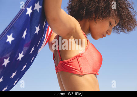 Woman in bikini holding drapeau américain sur la plage Banque D'Images