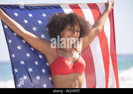 Woman in bikini holding drapeau américain sur la plage Banque D'Images