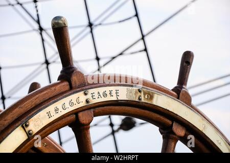 Le "Eagle" est la formation de voile navire de la Garde côtière des États-Unis situé dans le port de Hambourg sur l'Pauli-Landungsbrucken. Détail de la roue de direction avec garnitures et la gravure du nom du navire. À l'origine un navire de haute mer de la Marine allemande avec le nom "Horst Wesel', le trois-mâts est allé après la fin de la guerre en 1946 comme une réparation en nous. Traditionnellement, tous les navires de la Garde côtière canadienne sont appelés couteaux. Par conséquent, le USCGC Prafix  = United States Coast Guard Cutter. Comme la formation allemande de voile navire 'Gorch Fock', elle est l'un des six navires à voile de Banque D'Images