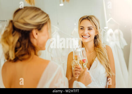 Deux jeunes mariées qui retentit verres de champagne ensemble. Banque D'Images