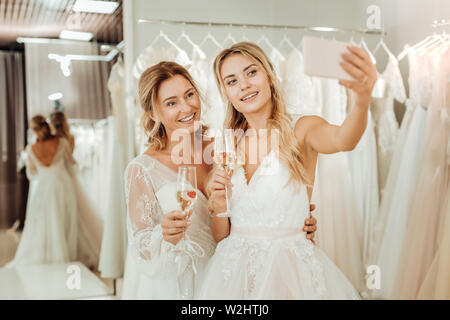 Deux jeunes mariées en tenant un salon du mariage dans un selfies. Banque D'Images