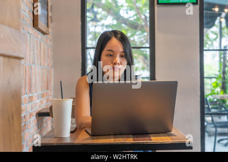 Black hair woman working on laptop at table Banque D'Images
