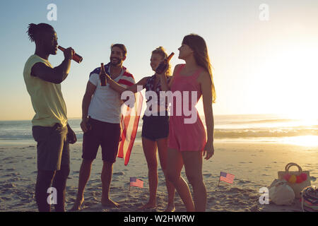 Groupe d'amis de boire une bière à la plage pendant le coucher du soleil Banque D'Images