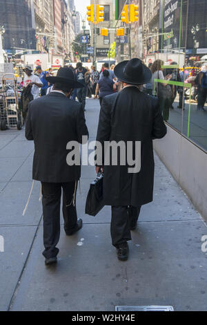 Deux hommes d'affaires juifs orthodoxes à pied vers le bas 47e rue, près de la 6e Avenue, dans la zone connue sous le nom de Diamond District à Midtown Manhattan. Banque D'Images