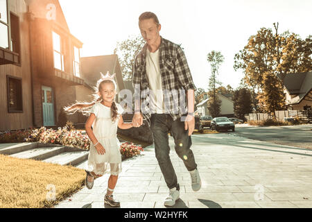 Jeune père élégant en chemise à carreaux et jeans jouer avec petite fille Banque D'Images