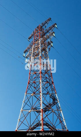 Vue du bas d'un pylône d'électricité à haute tension contre le ciel bleu en journée ensoleillée. Transmission de puissance haute tension tower. L'ingénierie de puissance. Banque D'Images