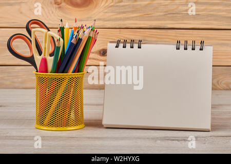 Crayons dans un panier métallique et carnet vierge. Banque D'Images