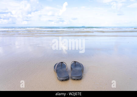 Chaussures ont été placés sur la plage par la mer, qui reflètent le ciel. Donnant la sensation de repos, de congés d'été long travail de longues vacances concept Banque D'Images