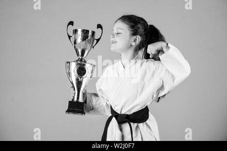 De souligner leurs réalisations. Kid forte et confiante. Petit enfant fille en kimono blanc avec ceinture. Karate fighter enfant. Karate sport concept. Compétences d'auto-défense. Le karaté donne un sentiment de confiance. Banque D'Images