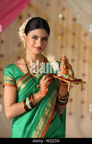 Portrait of a woman holding Ganesha statue Banque D'Images