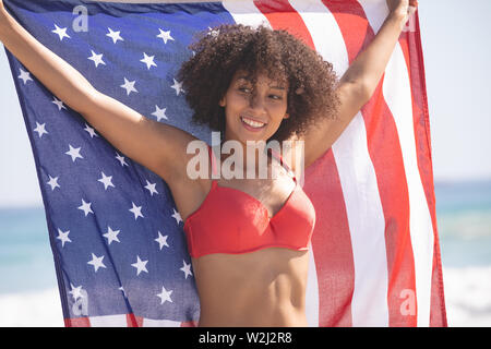 Woman in bikini holding drapeau américain sur la plage Banque D'Images