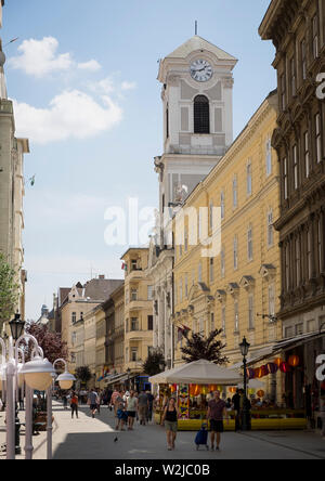 Scène de rue sur Vaci Utca avec la tour de l'église catholique de Budapesti Szent Mihály église-Lycée Banque D'Images