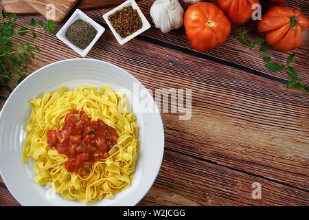 Tagliatelles faites maison avec de la sauce ratatouille. La moitié des pâtes faites maison, des tomates, des œufs frais, l'ail, le sel, l'origan, le poivre et le basilic. Banque D'Images