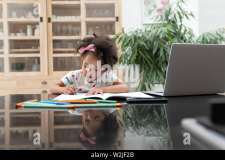 Petite fille fait ses devoirs sur une table à la maison Banque D'Images