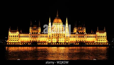 Le Parlement hongrois édifice adjacent à la rivière du Danube, éclairé la nuit. Banque D'Images