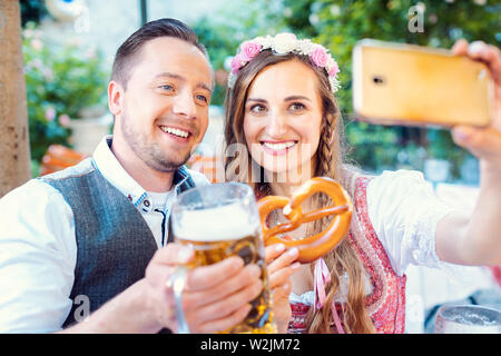 Couple dans le jardin de la bière allemande de prendre une photo avec le téléphone selfies Banque D'Images