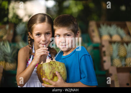 Frère et soeur de boire un verre de noix de coco ensemble. Banque D'Images