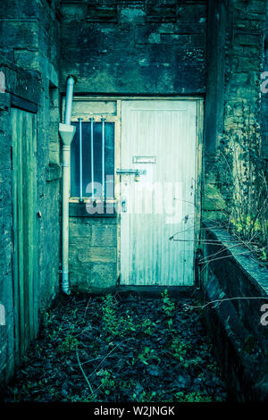 Une fenêtre et porte verrouillée pour le sous-sol de et ancien bâtiment en pierre, UK Banque D'Images