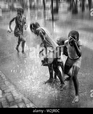 Les enfants jouent sous l'eau qui s'écoule des toits ci-dessus lors d'une descente torrentielle dans le centre de la Havane. Banque D'Images