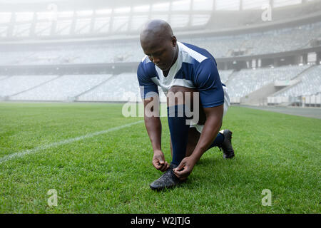 African American male rugby player attacher ses lacets dans le stade Banque D'Images