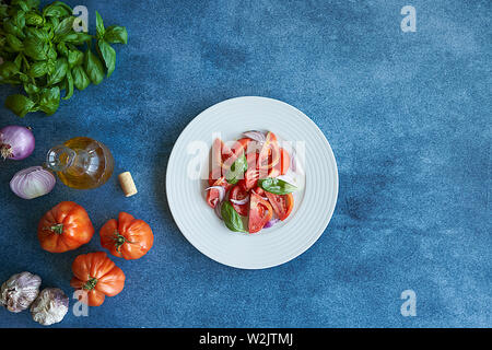 Salade de tomates légumes avec l'huile d'olive extra vierge, de l'oignon violet pourpre, l'ail et le basilic. Accompagné d'une bouteille d'huile d'olive extra vierge, violet o Banque D'Images