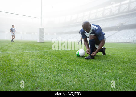 African American male rugby player attacher ses lacets dans le stade Banque D'Images