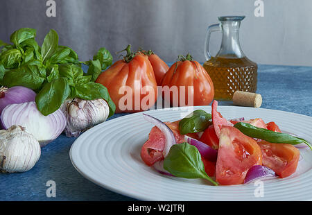 Salade de tomates légumes avec l'huile d'olive extra vierge, de l'oignon violet pourpre, l'ail et le basilic. Accompagné d'une bouteille d'huile d'olive extra vierge, violet o Banque D'Images