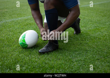 African American male rugby player attacher ses lacets dans le stade Banque D'Images