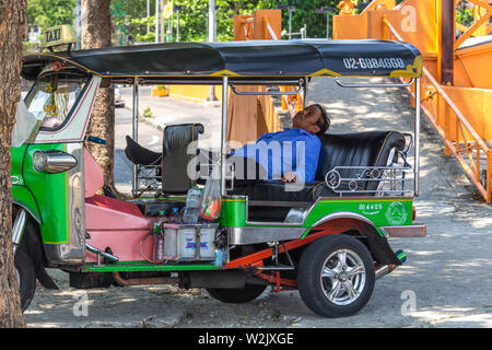 Bangkok, Thaïlande - 14 Avril 2019 : Taxi Driver dormir dans son tuk tuk garé près de la rue Banque D'Images