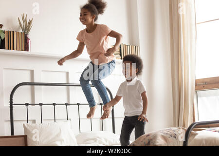 Happy little kids africains boy and girl jumping on bed Banque D'Images