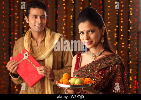 Portrait of a woman holding pooja thali avec son mari la regardant Banque D'Images