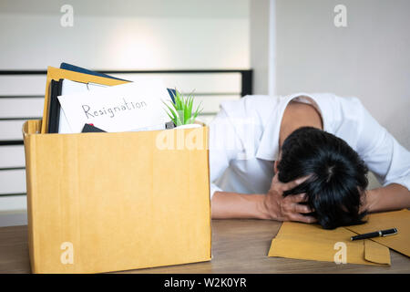 Stressed businessman va être démission et effets personnels d'emballage société et fichiers dans boîte en carton brun, changeant et démissionnera de travail conceptuel Banque D'Images