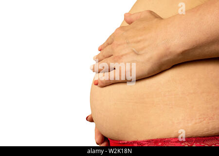 La grossesse après 40 ans concept. Plus le ventre de la femme enceinte close up image sur fond isolé. De mains avec les rides et le relâchement cutané Banque D'Images