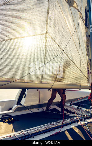 L'homme sur un catamaran voile derrière la voile. Loisirs d'été rétro-éclairé. Banque D'Images