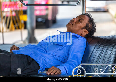 Bangkok, Thaïlande - 14 Avril 2019 : Taxi Driver dormir dans son tuk tuk garé près de la rue Banque D'Images